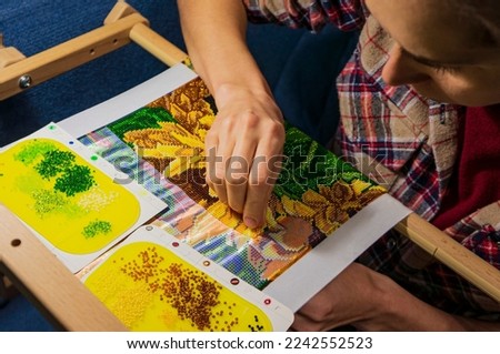 Bead embroidery pattern. Weaving from beads. The woman is fond of weaving from beads. Royalty-Free Stock Photo #2242552523