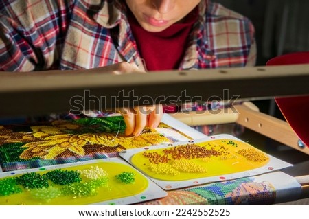 Bead embroidery pattern. Weaving from beads. The woman is fond of weaving from beads. Royalty-Free Stock Photo #2242552525
