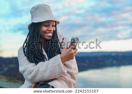 Female black tourist looking at river from a old city fortress, she's taking pictures of the view