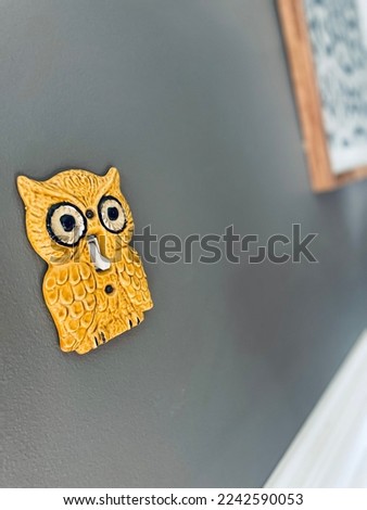 A picture of a vintage owl light switch on a gray wall.