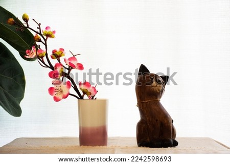 Interior decoration furniture and wooden cartoon cat with ceramic vase and sakura flower branch on white curtain background in house home living room for thai people rest relax at Nonthaburi, Thailand