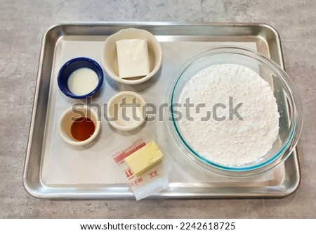 A baking tray with the ingredients for making butter cream frosting on top.
