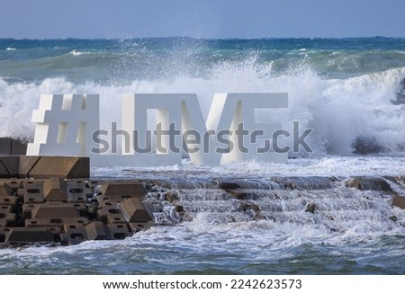 Waves crash on the word love in turbulent ocean waters