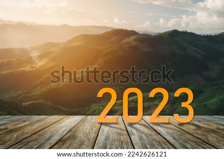 Happy new year 2023,2023 symbolizes the start of the new year. The letter start new year 2023 on the wooden table terrace sunset landscape mountain environment ecology or greenery wallpaper concept.