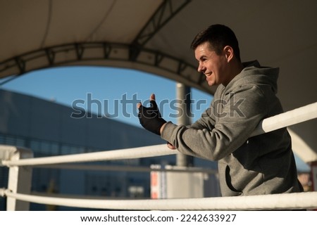 Caucasian male boxer resting in the ring outdoors. 