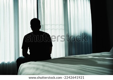 Silhouette depressed man sadly sitting on the bed in the bedroom. Sad asian man suffering depression insomnia awake and sit alone on the bed in bedroom. Depression health people concept. Royalty-Free Stock Photo #2242641921