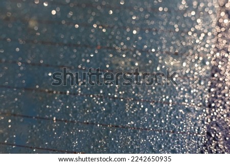 Water drops on car rear window with heating stripes visible in the glass.