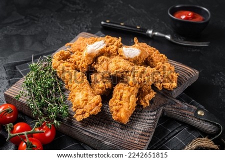 Dip fried Breaded chicken breast strips with tomato ketchup on a wooden board. Black backgrund. Top view. Royalty-Free Stock Photo #2242651815
