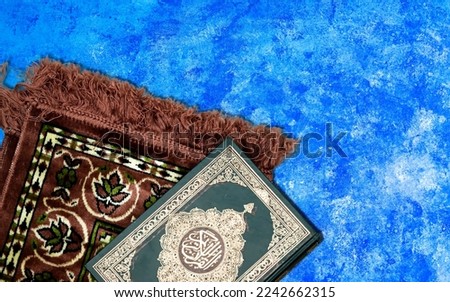 Holy Quran with Arabic calligraphy meaning of Al Quran and prayer mat with copy space for Ramadan (Month of fasting) or for eid