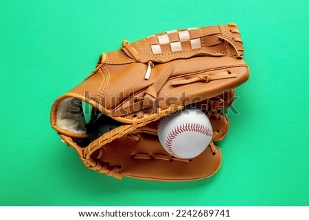 Catcher's mitt and baseball ball on green background, top view. Sports game