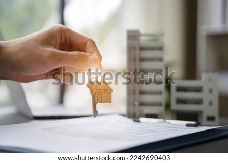 home loan officer gives the house keys to the client after signing a real estate contract with an approved mortgage application regarding the offer of mortgage loans and home insurance.