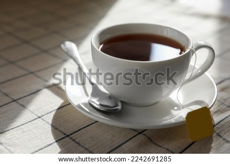 Bag of black tea in cup on table, closeup. Space for text