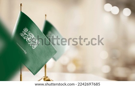 Small flags of the Saudi Arabia on an abstract blurry background.