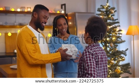 African-American parents presenting gift box to cute son for christmas. Portrait ofAfrican-American-american mother and father giving new year present to happy preteen son