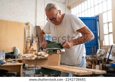 Carpenter working on wood craft at workspace producing wooden furniture with professional tools for crafting. High quality photo