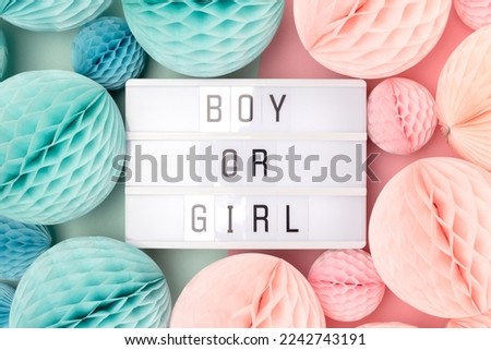 Boy or girl. Lightbox with letters and tissue paper balls in a pink and blue colors. Gender reveal party concept. 
