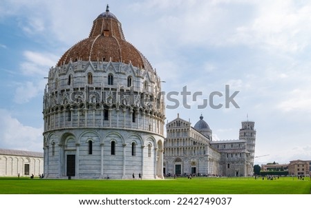 Leaning tower of Pisa Italy with Basilica Cathedral on a bright summer day with green grass low angle.  Royalty-Free Stock Photo #2242749037
