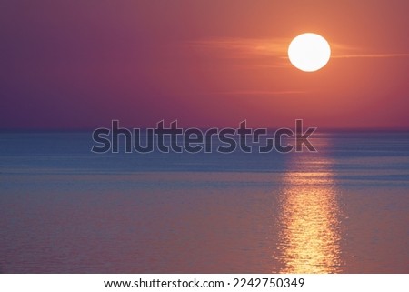 Defocused photography. Incredible beautiful pink sunset over the Baltic sea. Sun disc hanging over the horizon line. The sea is calm and peaceful during this magic sunny summer sunset time 