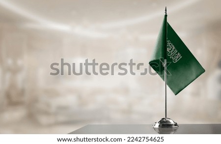 A small Saudi Arabia flag on an abstract blurry background.