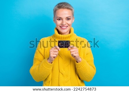 Photo of cheerful shopaholic blonde short hair lady wear yellow sweater demonstrate new credit card promo shopping isolated on blue color background