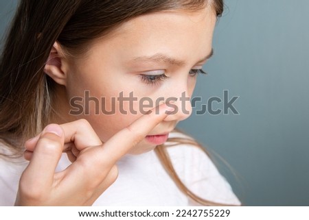 Little child girl inserting a transparent contact lens into her eye on gray background. The concept of ophthalmological poor sight correction Royalty-Free Stock Photo #2242755229