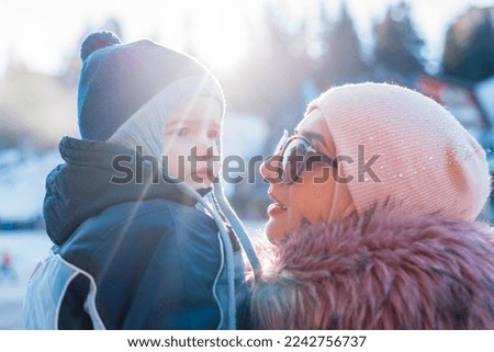 Happy family on the winter holiday vacation young mother and child son having a fun on snow outdoor.
