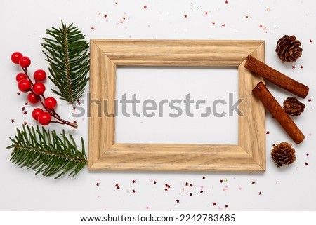 Composition with empty picture frame, Christmas decor and cinnamon on light background