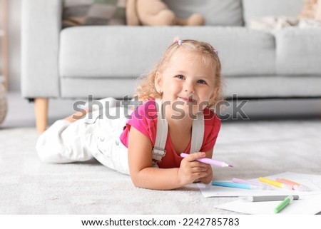 Cute little girl drawing with felt-tip pen on floor at home Royalty-Free Stock Photo #2242785783