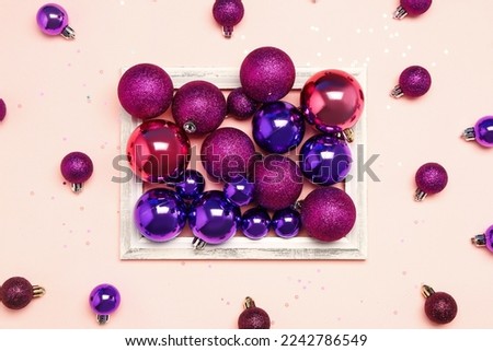 Composition with beautiful Christmas balls and picture frame on color background