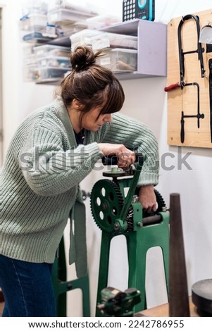 Concentrated craftswoman working and using special machine in jewelry workshop.