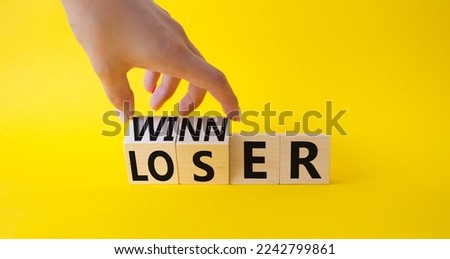 Winner and Loser symbol. Businessman hand turnes wooden cubes and changes word Looser to Winner. Beautiful yellow background. Business and Winner and Loser concept. Copy space