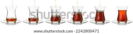 Process of pouring of tasty Turkish tea into glass cup on white background