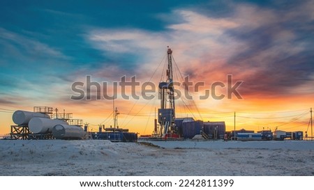 Equipment and infrastructure of the drilling rig for drilling oil and gas wells in the field of the Northern region. In the background, the colorful sky at the beginning of the polar day Royalty-Free Stock Photo #2242811399