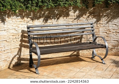 Beautiful wooden bench near brick wall on pavement outdoors