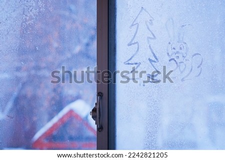 Frozen window glass with a pattern of a rabbit, a symbol of 2023. Sunlight through the pattern. Concept of christmas and new year. Selective focus.