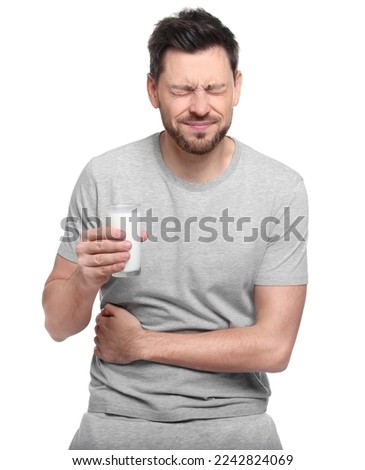 Man with glass of milk suffering from lactose intolerance on white background Royalty-Free Stock Photo #2242824069