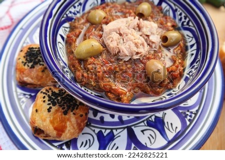 Grilled vegetables Tunisian salad with tuna and olives on top, close up view in Libyan traditional tableware with mini bread on the side  - daylight shoot  Royalty-Free Stock Photo #2242825221