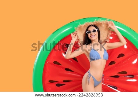 Happy young woman with beautiful suntan, hat, sunglasses and inflatable mattress against orange background, space for text