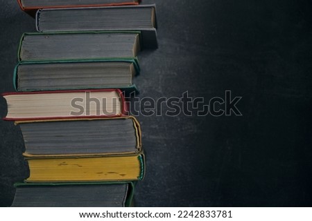 Stack of old battered books on retro photos against background concrete wall