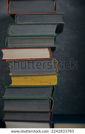 Stack of old battered books on retro photos against background concrete wall