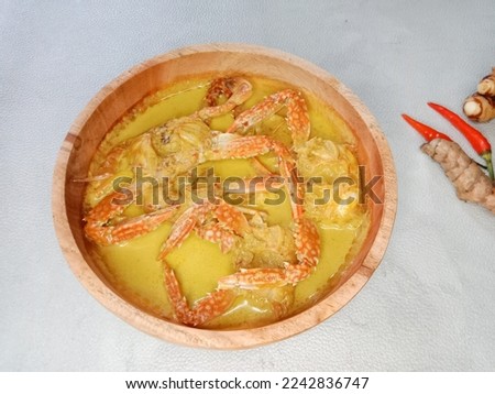 Crab Coconut Milk Soup or Kepiting Kuah Santan or Crab curry. Crab curry in wooden bowl isolated on white background. Indonesian food. Royalty-Free Stock Photo #2242836747