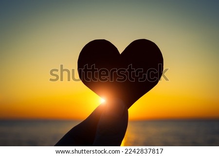 Vignetting Photo of Heart Shape Silhouette in the Hand on the Sunset on the Sea Background