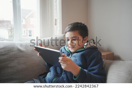 Education concept,School Kid holding tablet reading E-book for homework,Portrait happy Child playing game online on internet with friends,Young boy watching cartoon on digital pad,Kid sitting on sofa