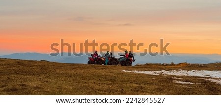Group of friends riding quad bike atv off road on the mountain at sunset adventure travel.