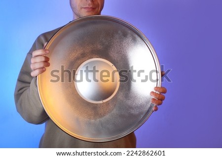 disassembly of a spotlight in a beauty dish by a person on a blue background Royalty-Free Stock Photo #2242862601