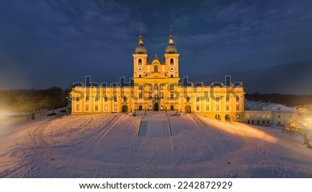 Aerial, late evening panoramic view of illuminated Minor Basilica of the Visitation of the Virgin Mary, pilgrimage church covered with snow. Blue hour, Christmas time, Moravia, Czech republic.
