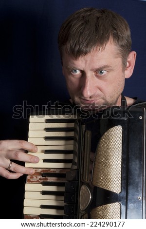 Portrait of a serious man playing old harmonica with damaged keys