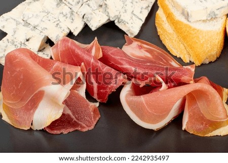 Prosciutto Tapas and Mold Cheese on Black Plate, Spanish Jamon Slices on Bread, Parma Ham , Sliced Serrano Canape, Iberico, Spanish Ham, Cured Meat Snacks for Wine