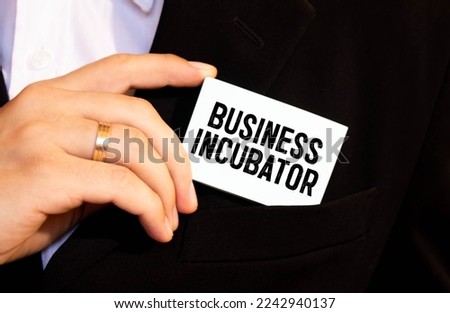 BUSINESS INCUBATOR text in office notebook with keyboard, magnifier and glasses , business concept