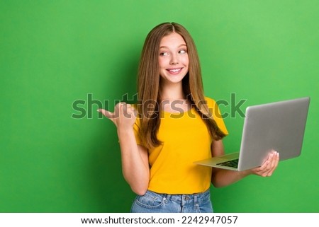 Photo of dreaming smiling girl teenager wear yellow t-shirt hold computer look empty space new coding courses isolated on green color background